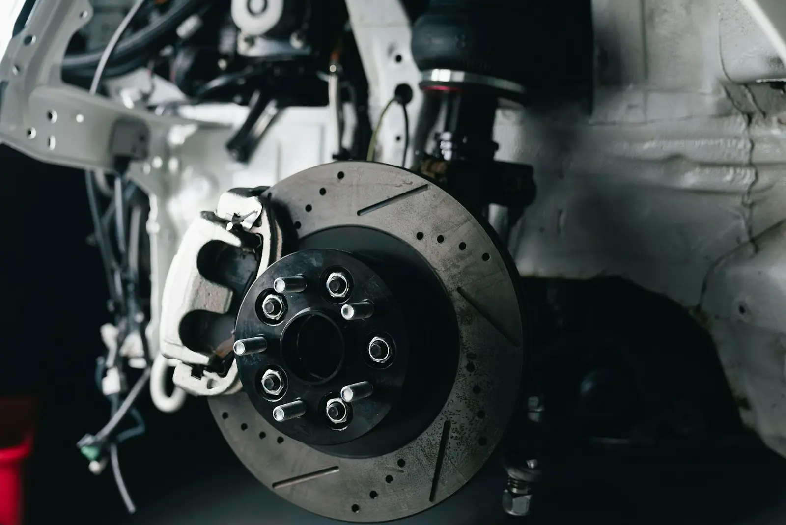Close-up of a drilled brake disc and red caliper on a raised car