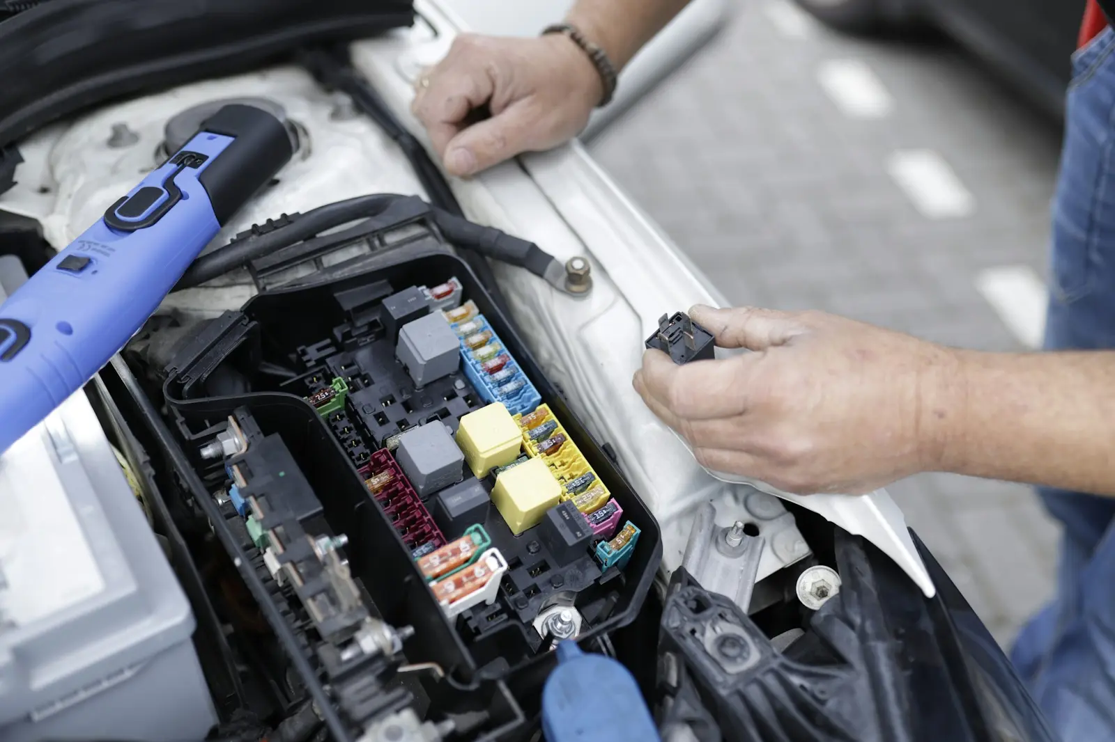 Mechanic’s hands testing the electrics in a car’s engine bay