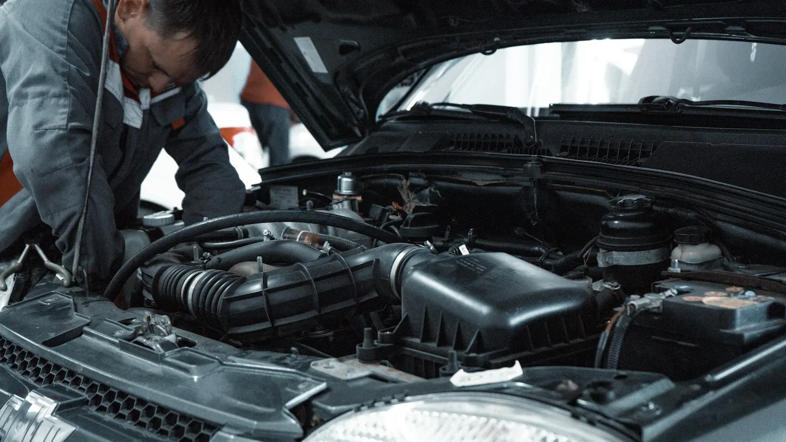 Mechanic inspecting a car’s engine bay with the bonnet open