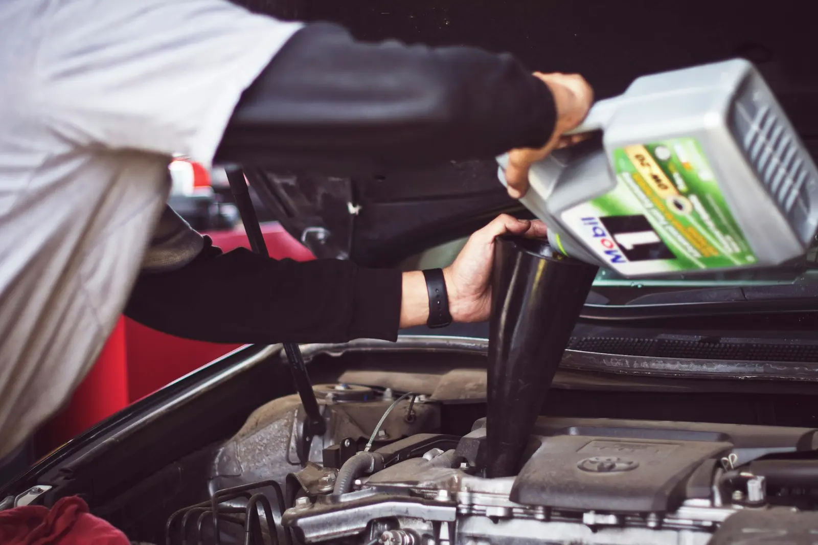 Fresh engine oil being poured into a car during a service