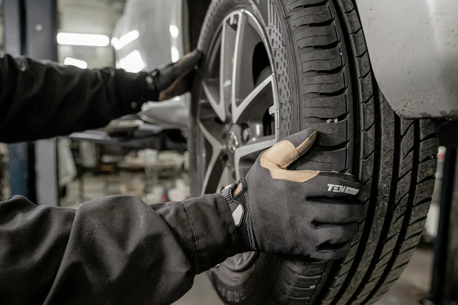 Gloved hands fitting a tyre and alloy wheel to a car